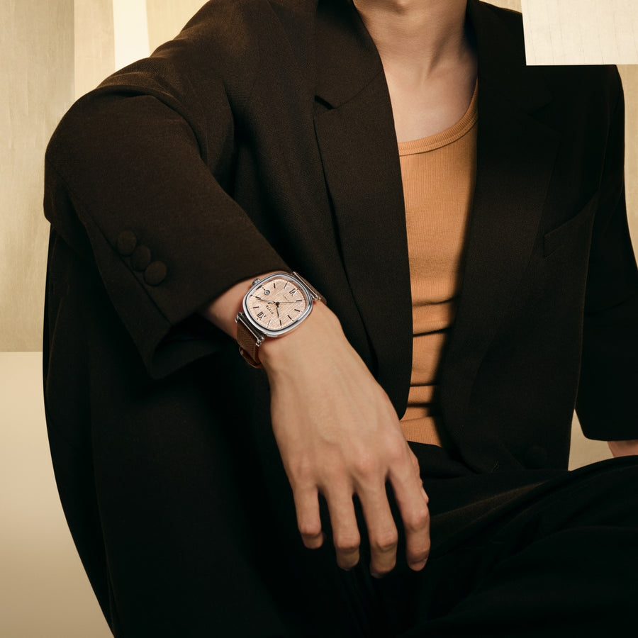 A FIYTA Tempered watch with a rose-toned dial and brown strap worn while seated in a dark jacket. (GA850028.WOK)