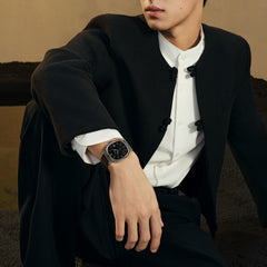 A FIYTA Tempered watch with a black dial and black strap worn with a dark jacket and white shirt. (GA850029.WBB)